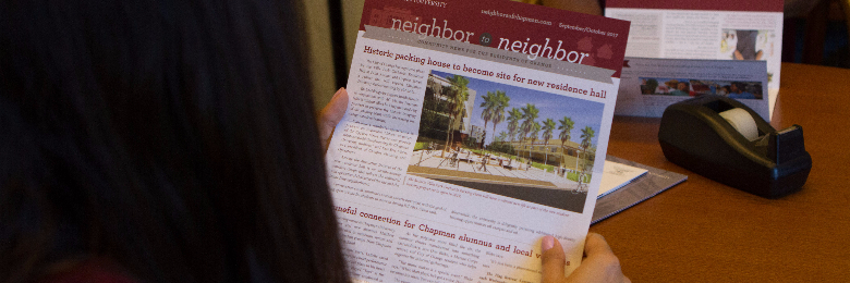 A student holds a copy of the Neighbor-to-Neighbor newsletter