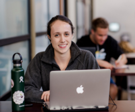 Student smiling at table with water bottle and computer