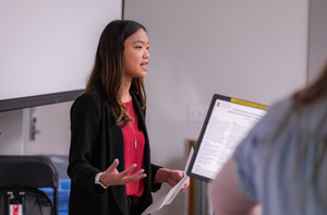 A student gives a presentation at a podium in front of an audience.