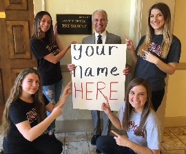 students gathered around President Doti in front of his office