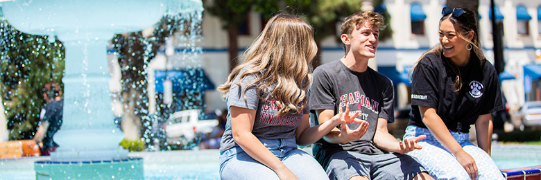 three students sitting near a fountain in the orange circle
