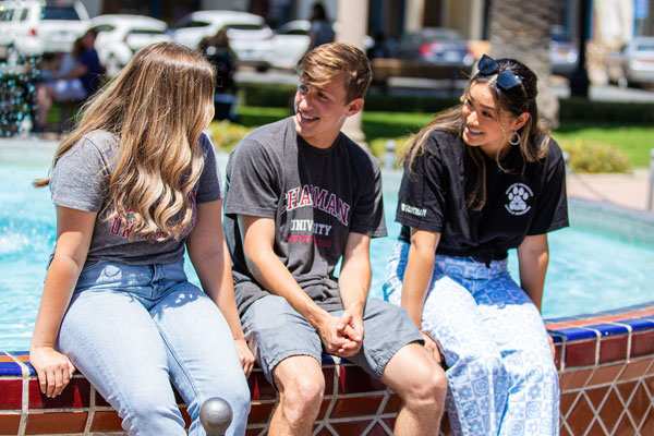 Three students sitting on a fountain