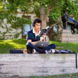 Student studies outdoors on campus