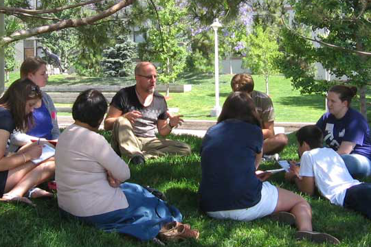 people gathered around spiritual leader on grass
