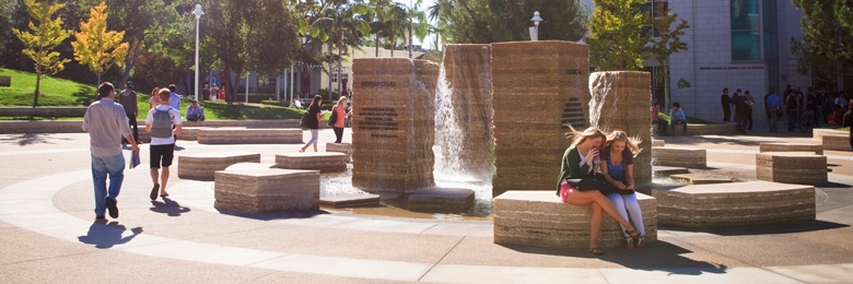 Students sit at the fountain at Atallah Piazza at Chapman University.