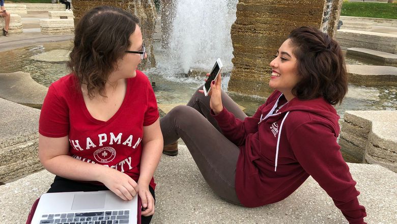Two Chapman students viewing content on a cellphone