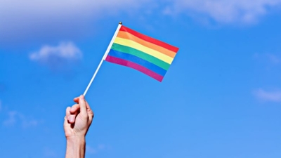 Hand holding a rainbow flag