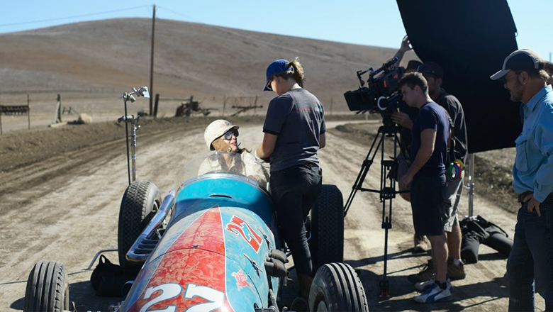 A student in a racecar on a film set
