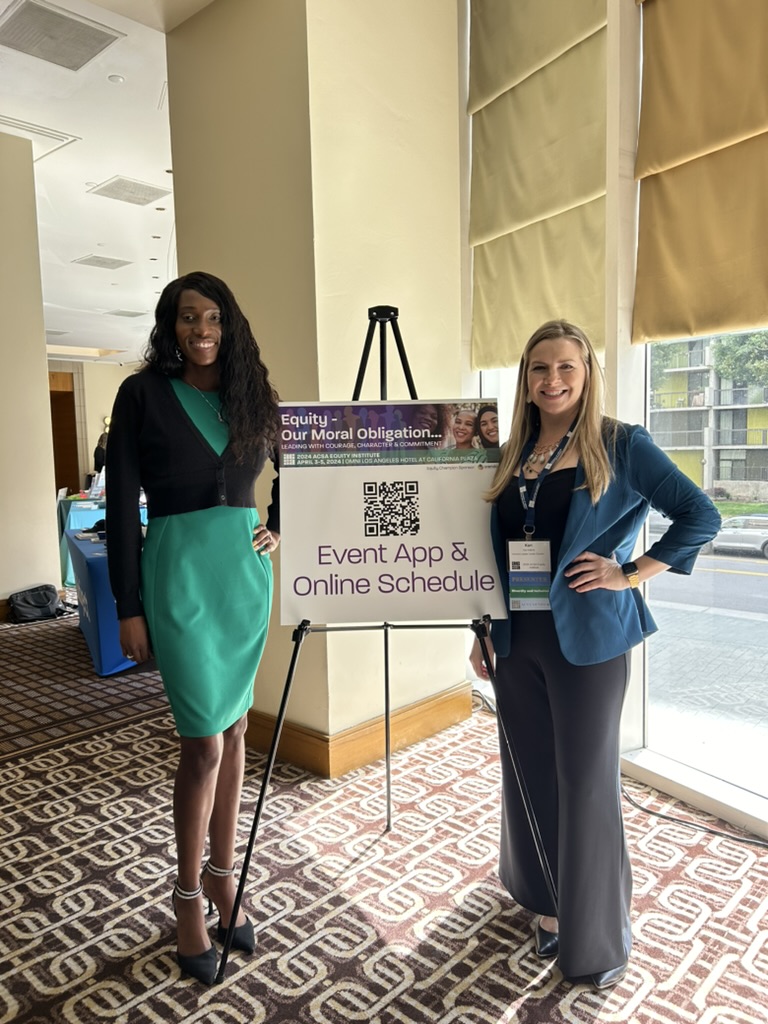 photo of two women standing in front of a sign 