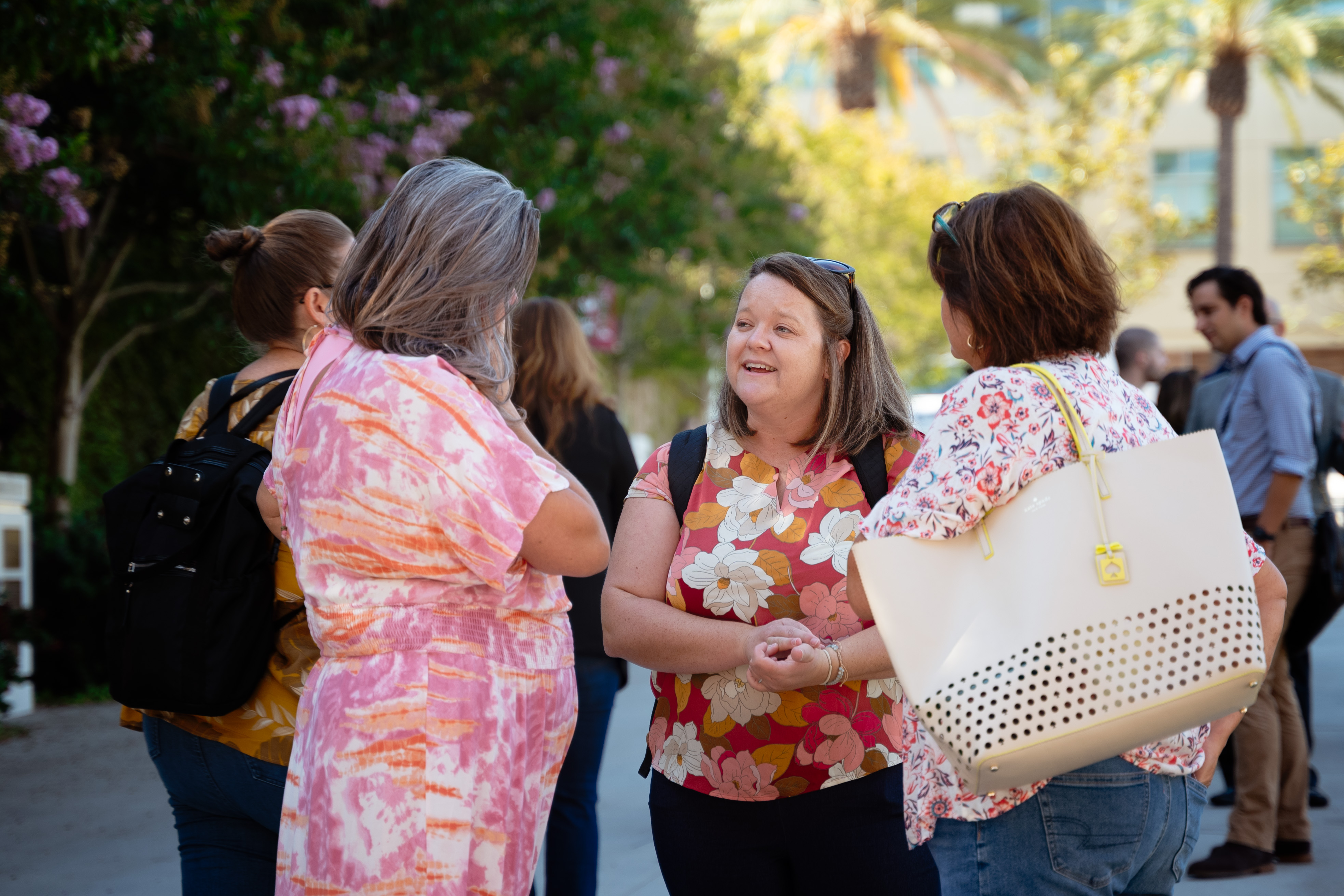 Three summit attendees conversing outside Musco Center for the Arts.
