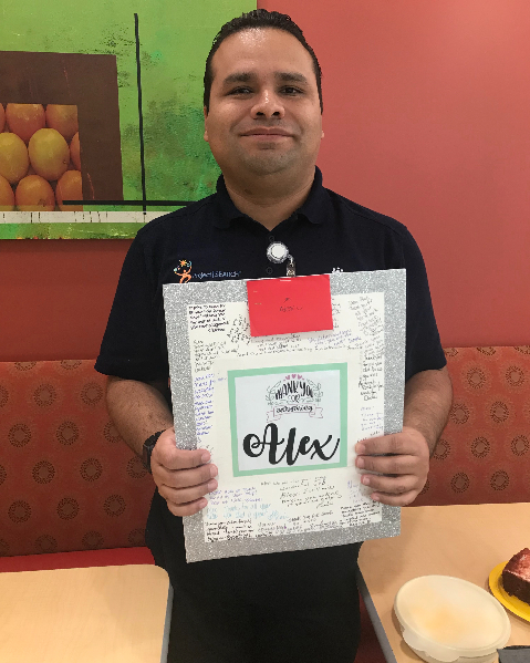 Alex Zavala is standing in the breakroom at Kaiser holding a thank you card from Kaiser staff