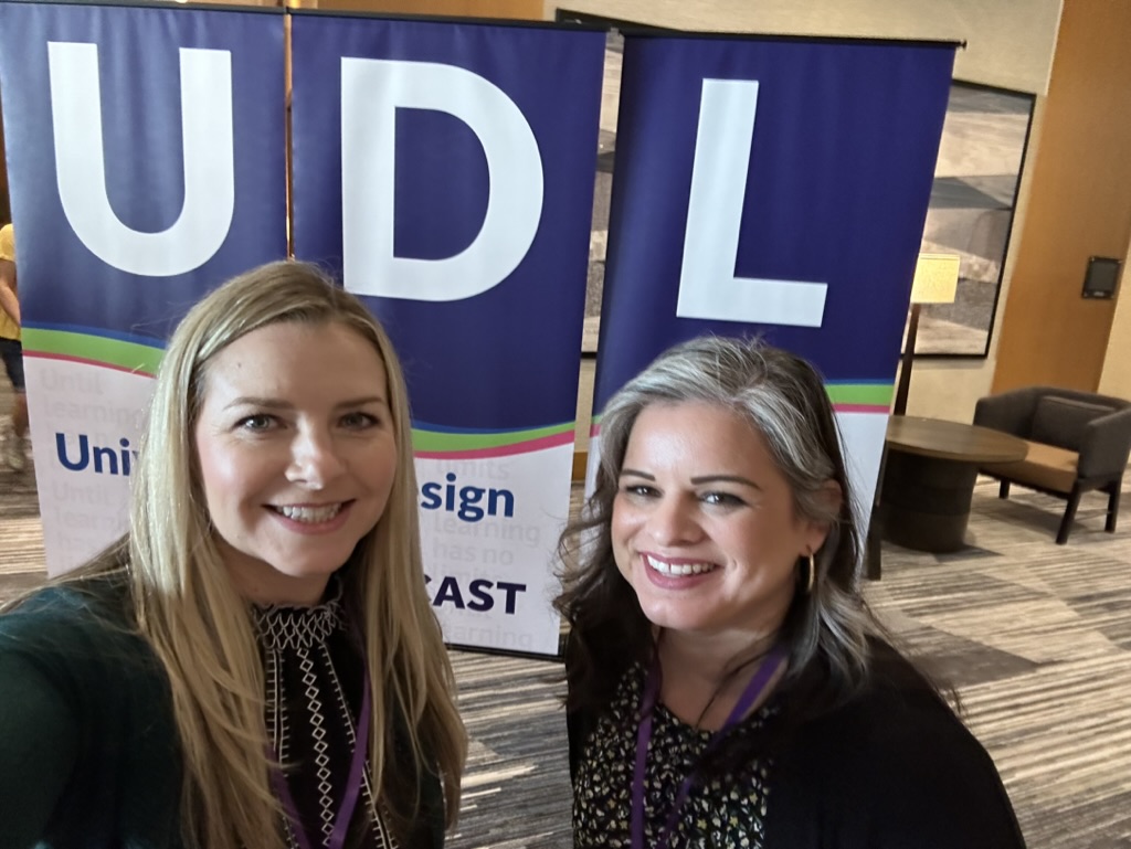 Audri and Kari standing in front of UDL banner 