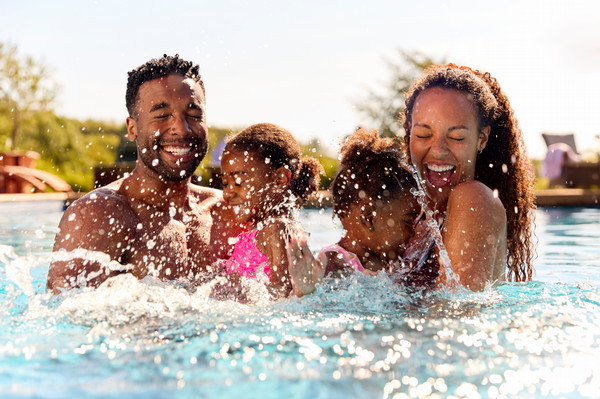 family on vacation in pool splashing water