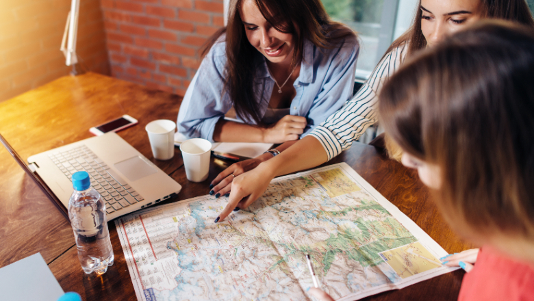 Women planning travel with a map and computers.