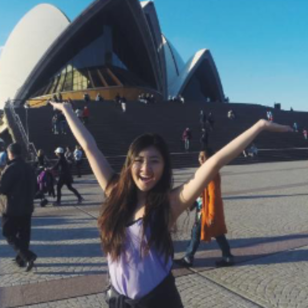 Student with her arms up in front of Sydney Opear House, Australia